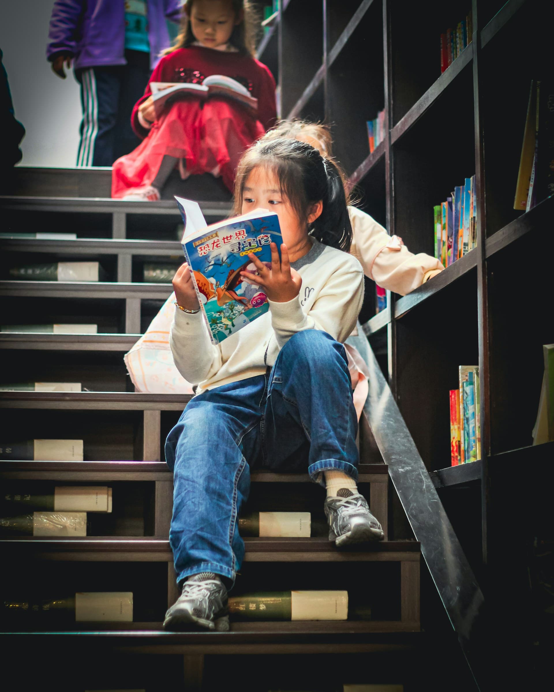 Ein Mädchen sitzt auf einer Bibliothekstreppe und liest in einem Buch