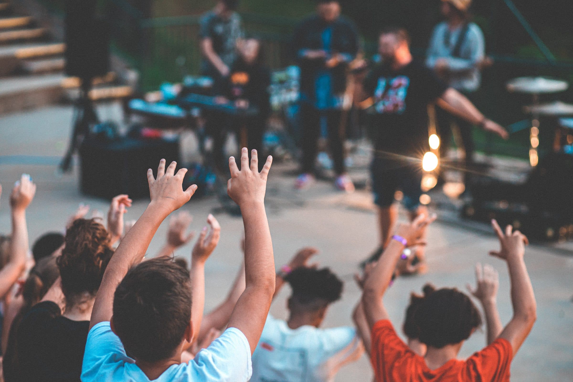 Kinder bei einem Open-Air-Konzert, die Hände in die Luft gestreckt