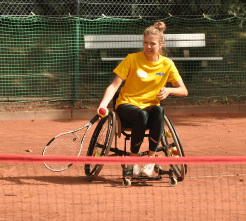 Eine Tennisspielerin im Sportrollstuhl auf dem Sandplatz